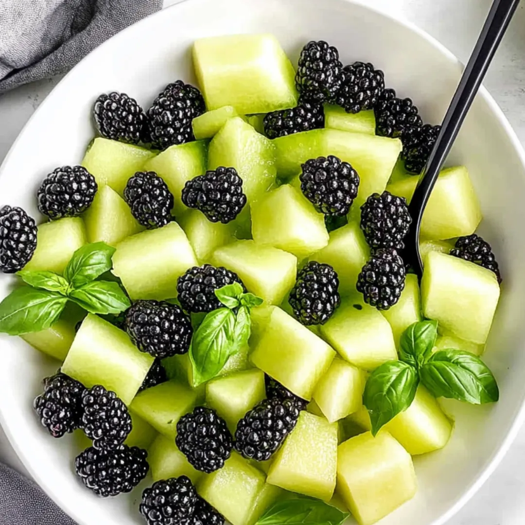 Eine Schüssel mit Obst, darunter Brombeeren, grüne Äpfel und Minze.