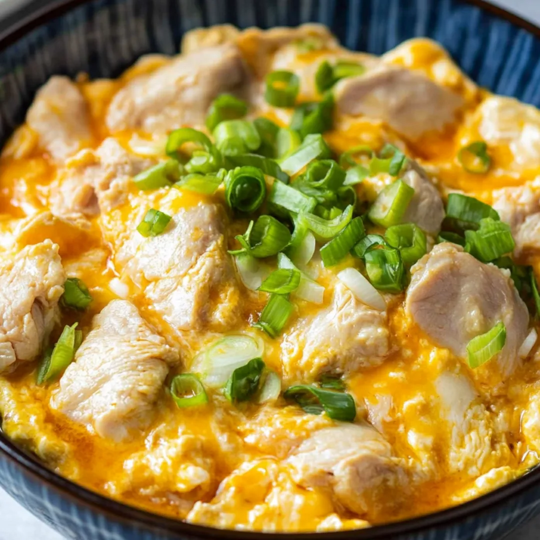Eine Schale Essen mit Frühlingszwiebeln und Hühnchen.