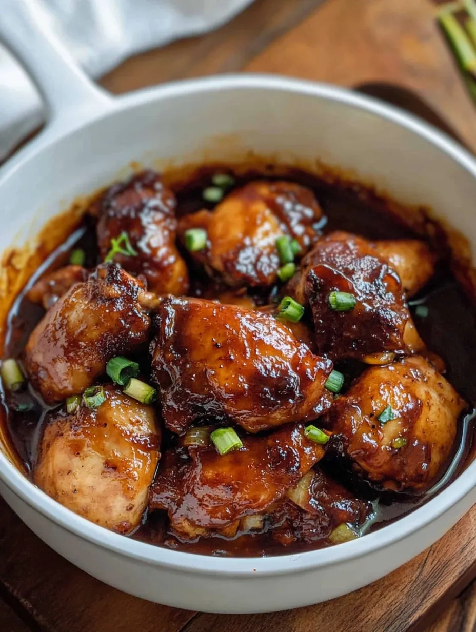 Eine Schüssel Hühnchen mit grüner Garnitur.