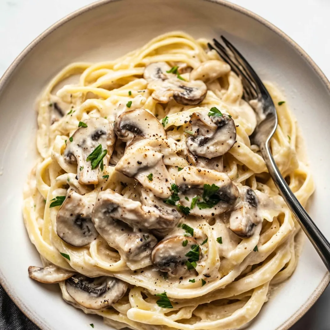 Ein Teller Pasta mit Pilzen und frischen Kräutern.