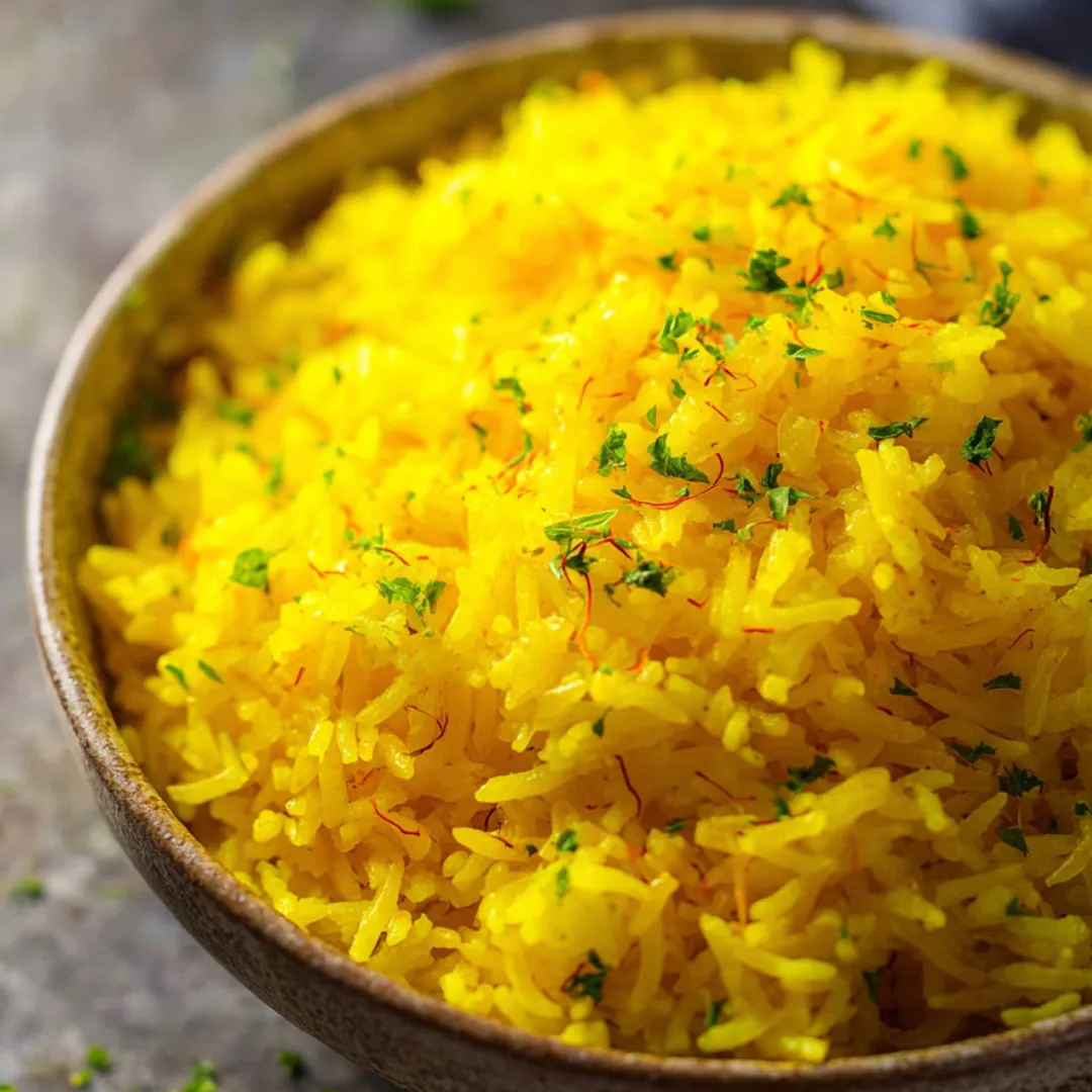 Eine Schüssel goldener Reis mit frischen Kräutern obendrauf.