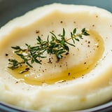 Eine Schüssel Kartoffelpüree mit Kräutern obendrauf.