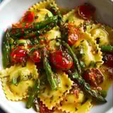 Eine Schüssel mit Pasta, Tomaten und Spargel.