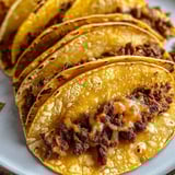Ein Teller mit Tacos, gefüllt mit Fleisch und Käse.