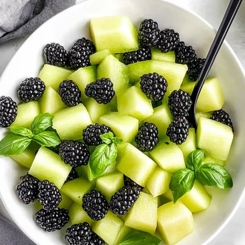 Eine Schüssel mit Obst, darunter Brombeeren, grüne Äpfel und Minze.