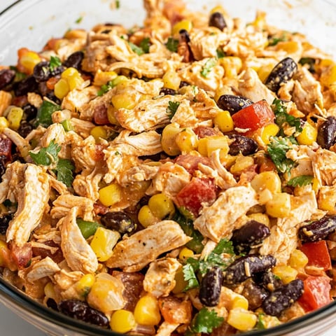 Eine Schüssel mit Hühnchen, Mais, Bohnen und Tomaten.